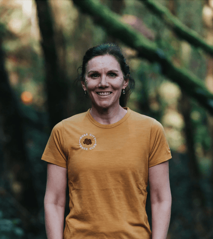 Emma, a Rose City Track Club member, wearing a yellow club shirt posing for a photo